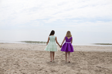 Niñas con vestidos de fiesta descalzas por la playa
