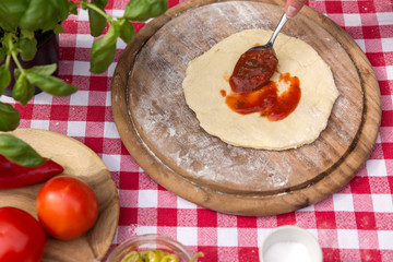 Pizzateig wird mit Tomatensoße belegt
