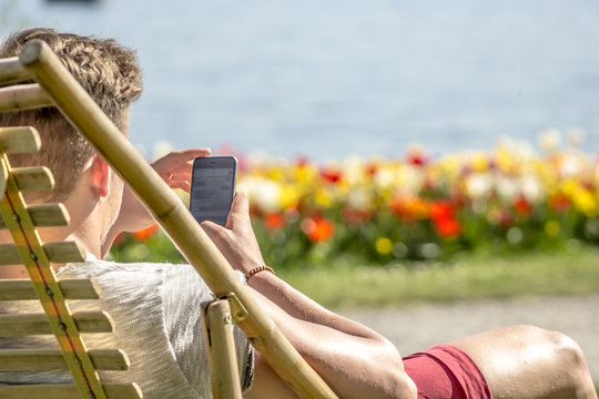 Jugendlicher mit Handy am See