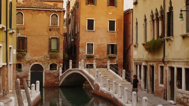 Medium shot of Venetian canal, buildings and bridge / Venice, Italy