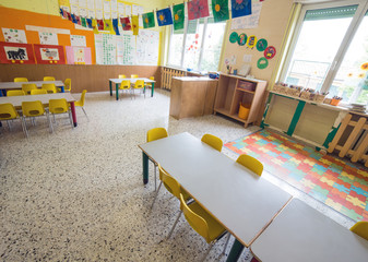 classromm of kindergarten with tables and small yellow chairs