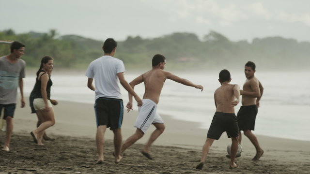 Wide panning shot of people playing soccer on beach / Esterillos, Puntarenas, Costa Rica