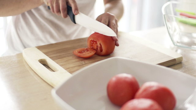 Woman slicing tomatokitchen, slow motion shot at 240fps
