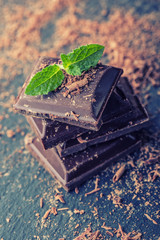 A few cubes of black chocolate with mint leaves.