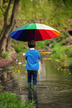 Cute Little Boy, Walking In A Pond On A Rainy Day, Playing And J