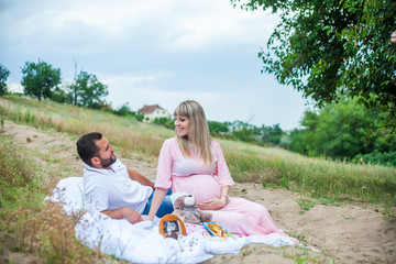 man and pregnant woman on a picnic in the countryside