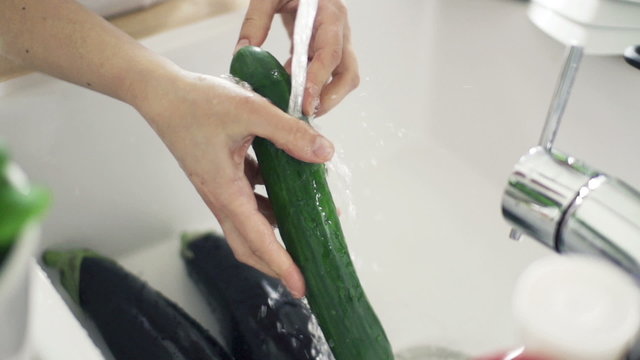 Woman washing cucumber under tap water, slow motion 240fps
