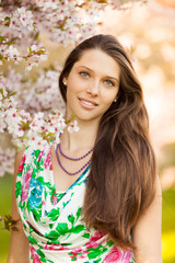 Naklejka premium Beautiful brunette woman in blooming orchard