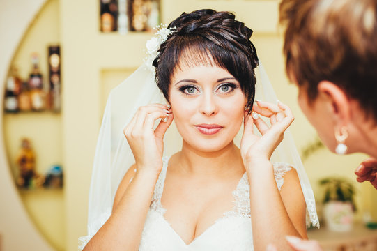bride holding earrings. Portrait of a gorgeous woman adjusting