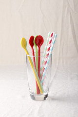 colorful spoon and stripped straw in clear glass