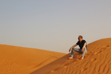 Fototapeta na wymiar Man sitting alone in the sunny desert