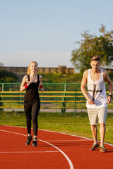 Fototapeta premium An attractive man and woman jogging on the track