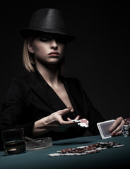 Beautiful young woman playing poker isolated on black background.