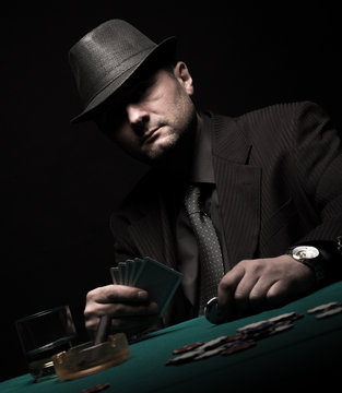 Male gambler playing poker isolated on black background.	