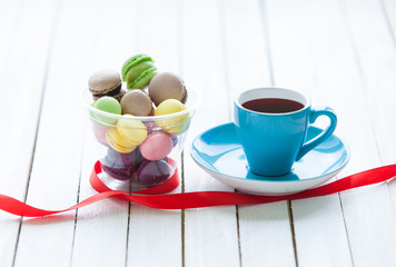 Cup of coffee and macarons near ribbon