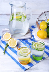 Fresh water with lemon and cucumber in glassware on wooden background