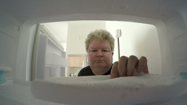 A man takes something out from empty freezer