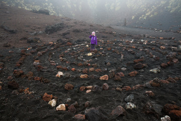 Child standing in spiritual spiral in Etna volcano crater