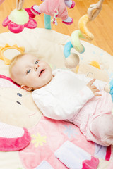portrait of baby girl lying on playing mat