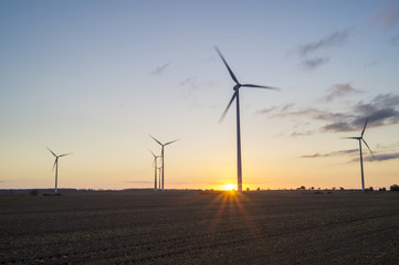 Wind generators turbines on sunset spring landscape 