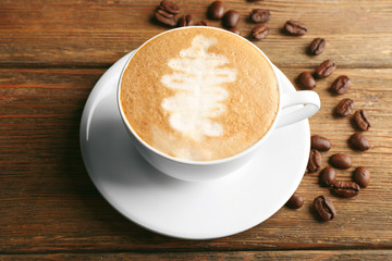 Cup of latte art coffee with grains on wooden background