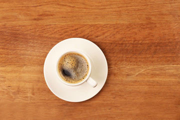 Cup of coffee on wooden table, top view