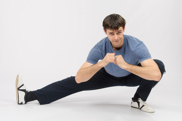 Obraz premium Athlete crouching stretches the muscles of right leg