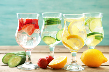 Glasses of different home made freshness healthy vitamin-fortified water on wooden table