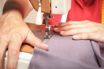 Close up of senior woman hands sewing on a sewing machine.