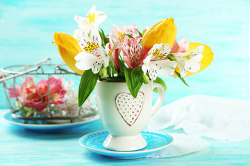 Beautiful flowers in cup, on color wooden background