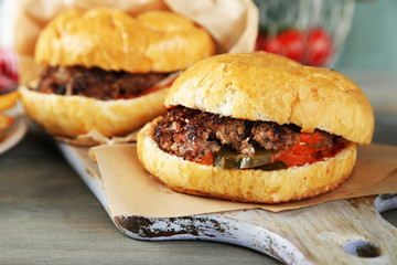 Tasty sandwich on cutting board, on color wooden background. Unhealthy food concept