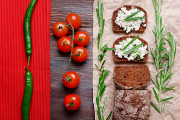 Bread with cottage cheese, greens and tomatoes on paper on table top view