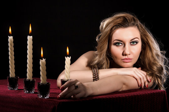 Beautiful young woman with bright green eyes near the candles