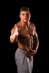 Fototapeta na wymiar muscle bodybuilder man hand with thumbs up on a black background