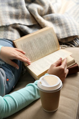 Fototapeta premium Young woman reading book, close-up, on home interior background