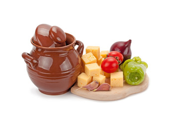 clay pot, cheese and vegetables on wooden board