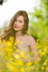 Beautiful young girl among yellow flowers