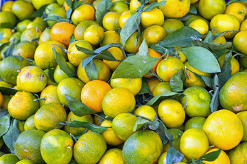 a few underripe tangerines in a wooden crate for sale
