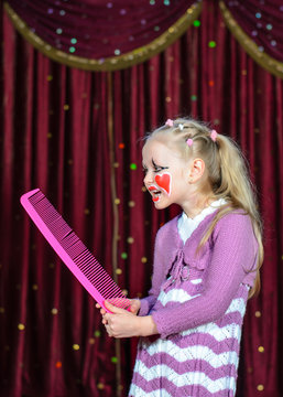 Girl Wearing Clown Make Up Holding Over Sized Comb