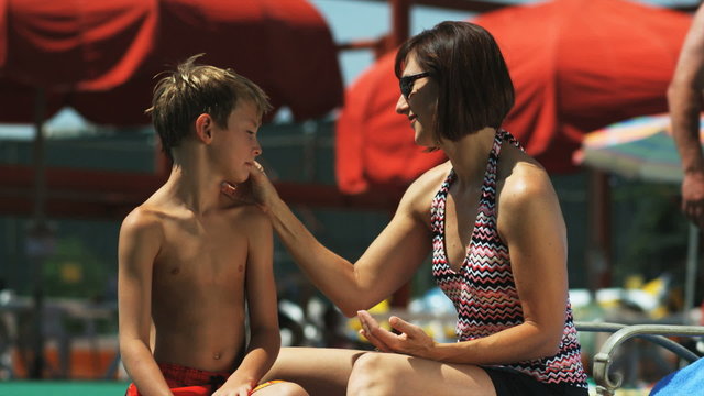 mother and son at a water park putting on sunscreen