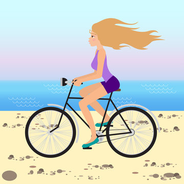 Girl rides a bicycle along the beach on sunset sky background