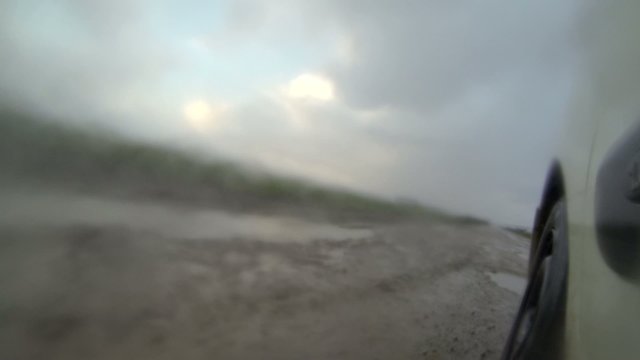Driving in the rain on a road with puddles and muddy water