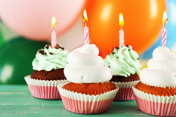 Delicious birthday cupcakes on table on bright background