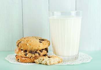 Tasty cookies and glass of milk on color wooden background