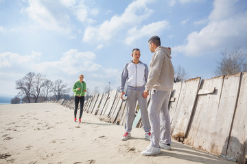 Three young people having a sports training on the beach