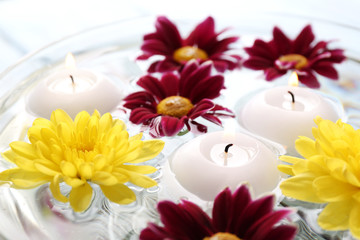Fototapeta na wymiar Bowl of spa water with flowers and candles, closeup