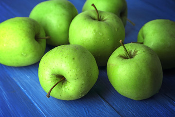 Green apples on color wooden table, closeup