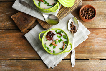 Mushroom soup on wooden table with napkin, top view