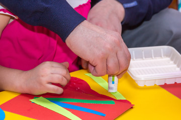 children and adults hands glue colored paper on application mast