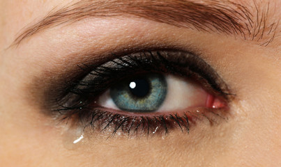 Obraz premium Eye of young woman with tear drop close up
